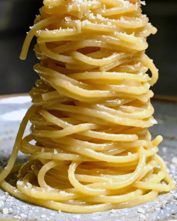 A towering nest of glossy spaghetti alla chitarra coated in a creamy egg and Pecorino sauce, topped with crispy guanciale.