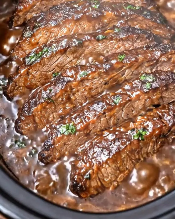Une tranche épaisse de brisket de bœuf tendre recouverte de sauce barbecue brillante.