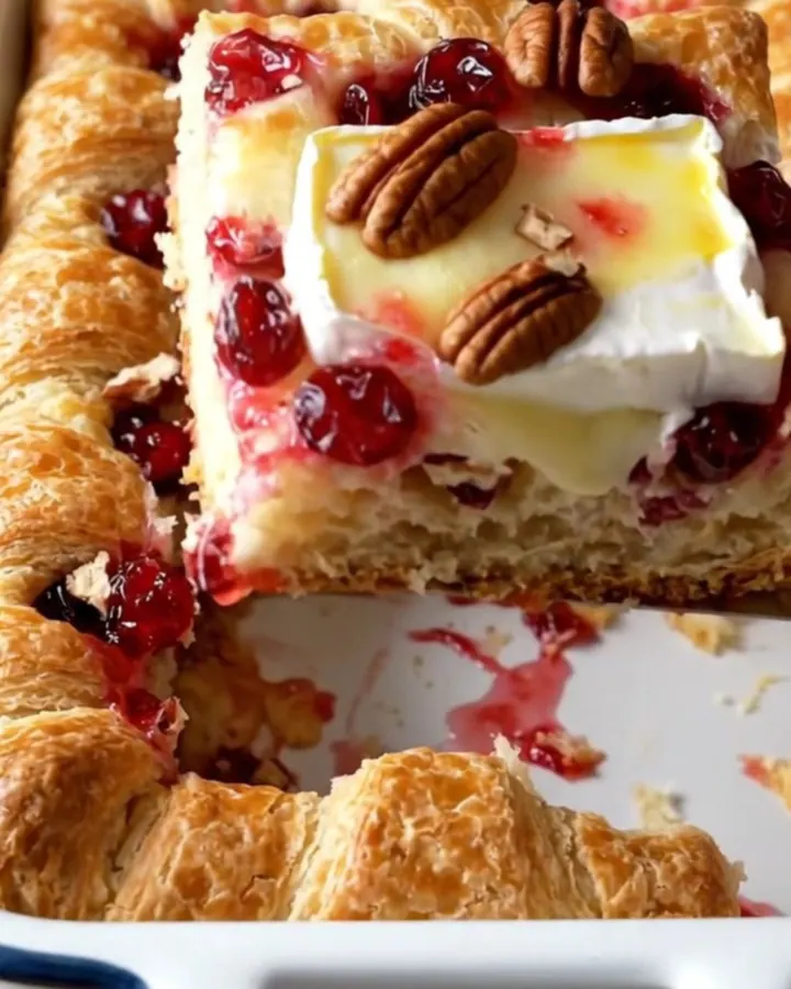 A rectangular baker filled with a golden, flaky cranberry brie crescent bake on a beige countertop.