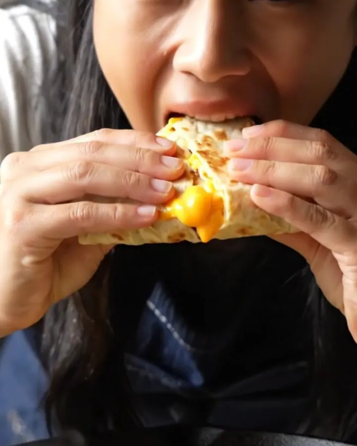 A crispy, golden-brown four-quadrant breakfast tortilla sliced in half to show molten cheese, bacon, and fluffy eggs.