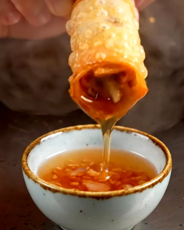 A close-up shot of golden-fried Peking duck spring rolls with a shattered, crispy texture.