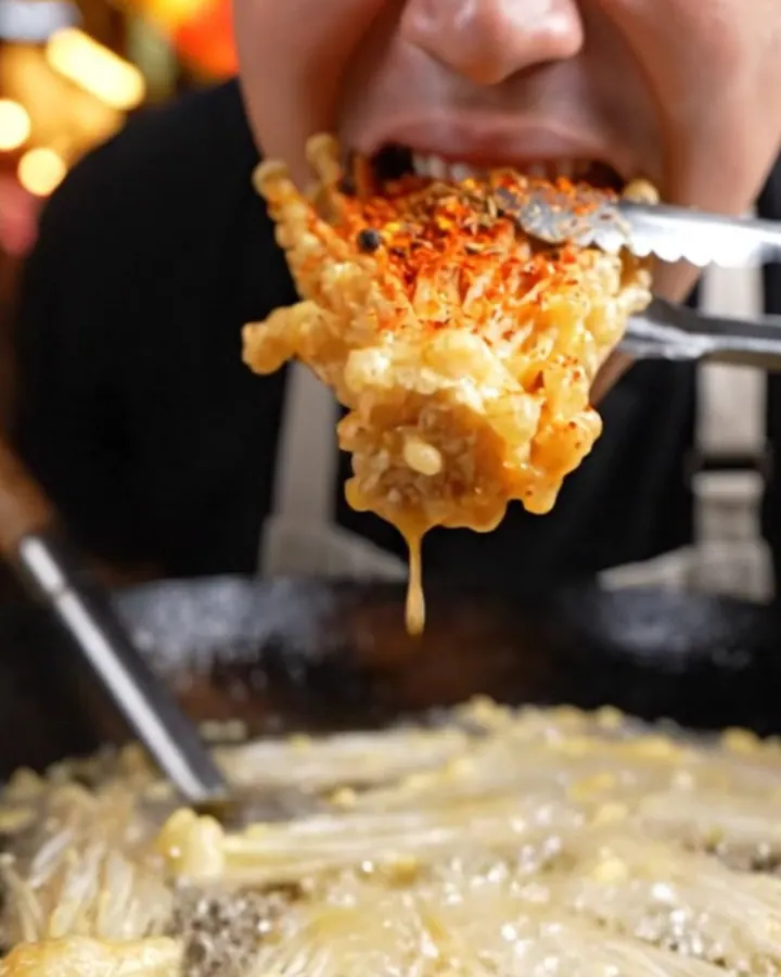 A golden, crispy cluster of fried enoki mushrooms dusted with vibrant red Sichuan mala spices.