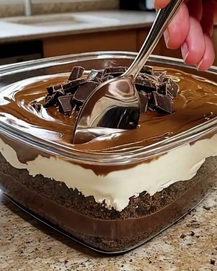 Dessert au chocolat en couches dans un plat carré en verre, nappage brillant et éclats de chocolat