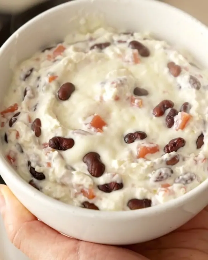A creamy black bean queso dip in a slow cooker topped with diced tomatoes and beans.