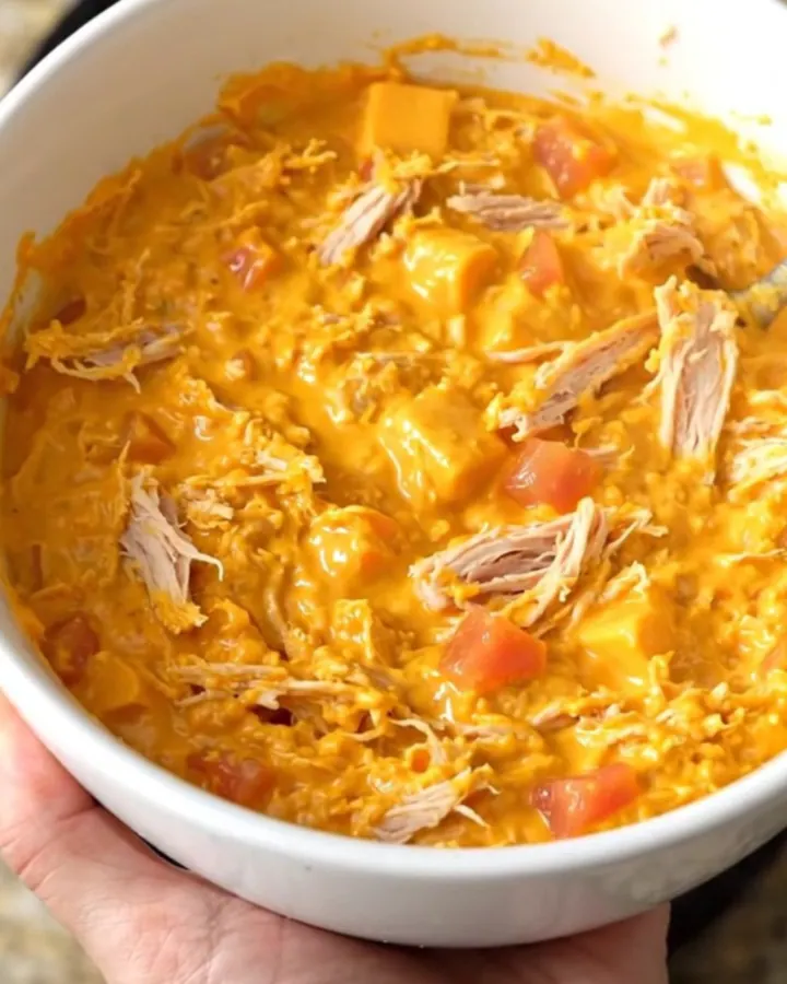 A warm, creamy queso dip with ground turkey and tomatoes in a black slow cooker.