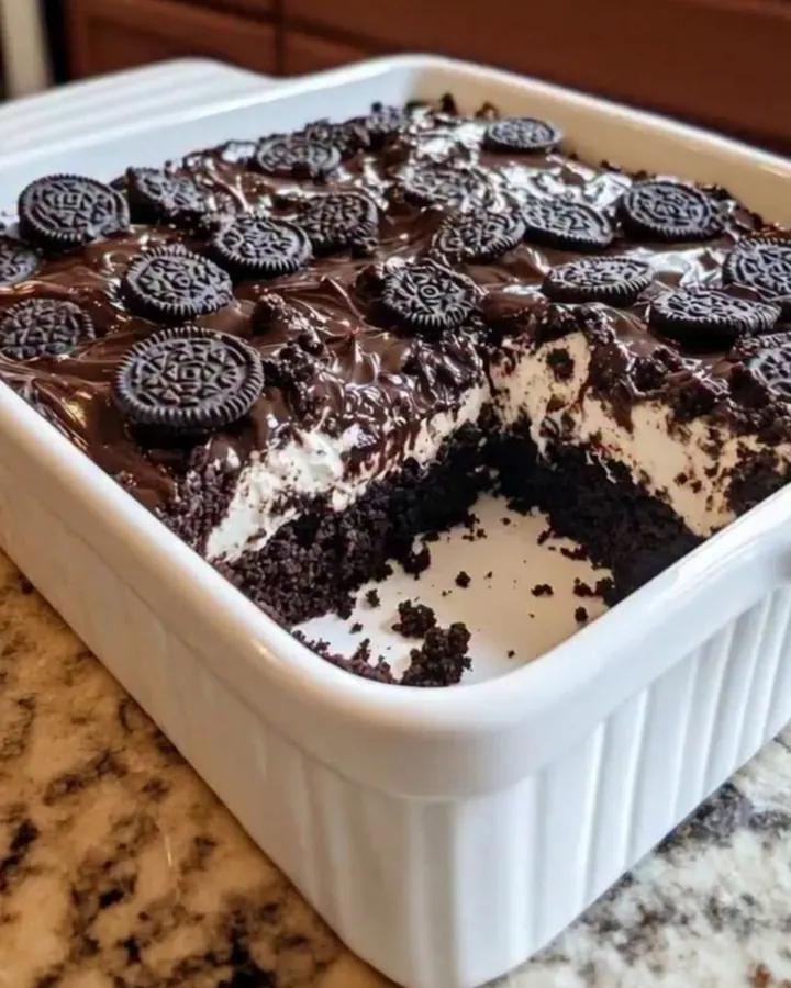 Gâteau Oreo earthquake dans un plat blanc, surface fissurée, une part retirée révélant des couches fondantes de fudge