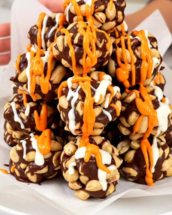 A top-down view of roasted peanuts, chocolate chips, and candy melts inside a black slow cooker insert.