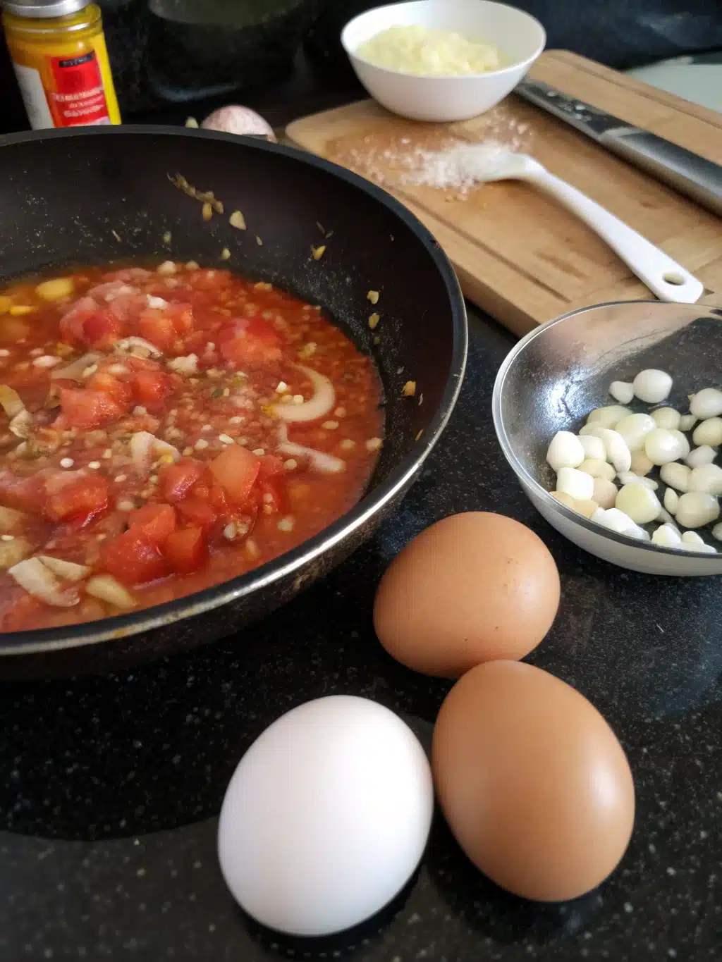 Cracking eggs into tomato sauce for Greek tomato eggs