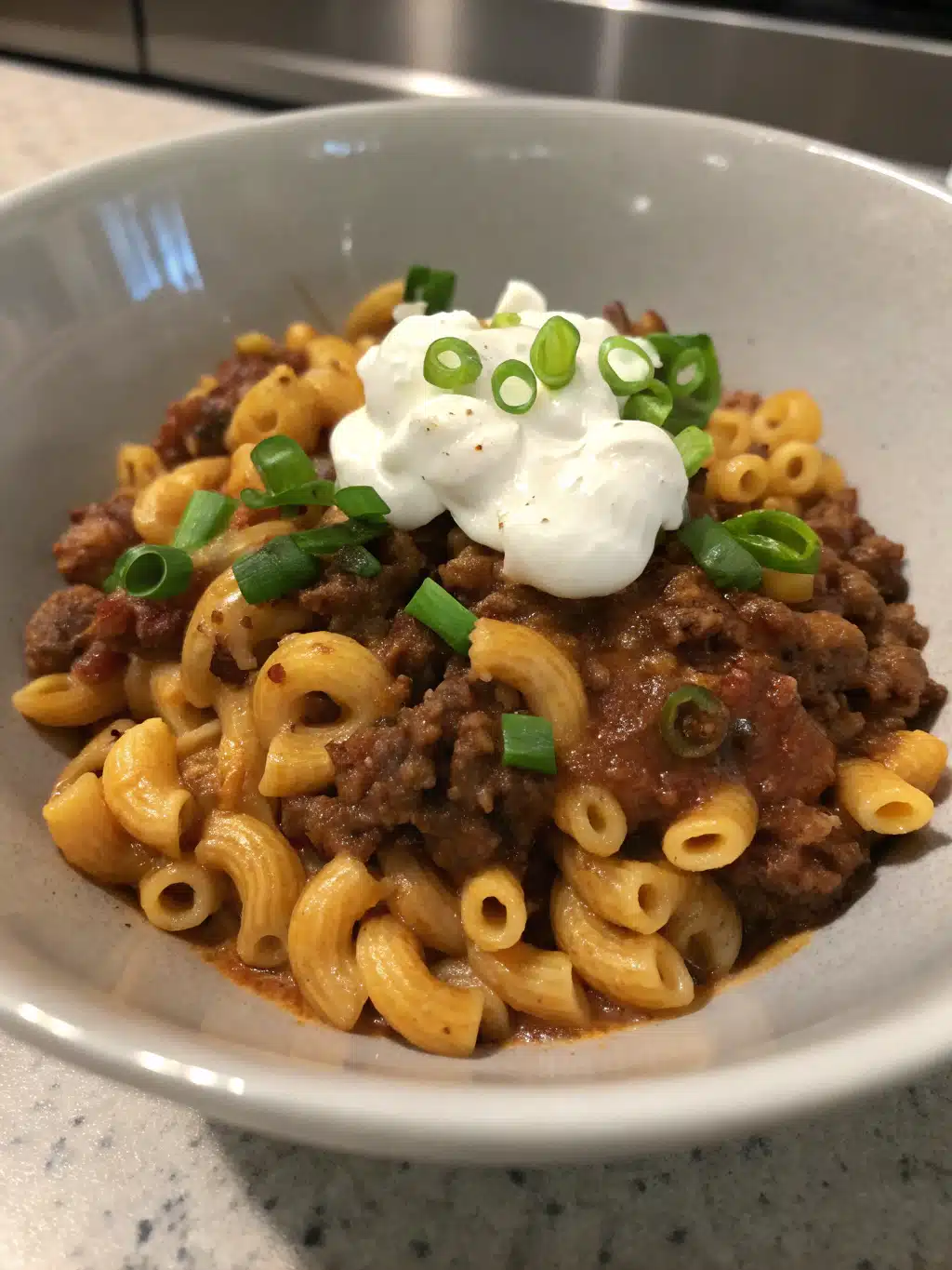 Creamy chili cheese pasta with ground beef and cheddar, topped with sour cream and green onions for a hearty, comforting meal. Ready in 30 minutes!