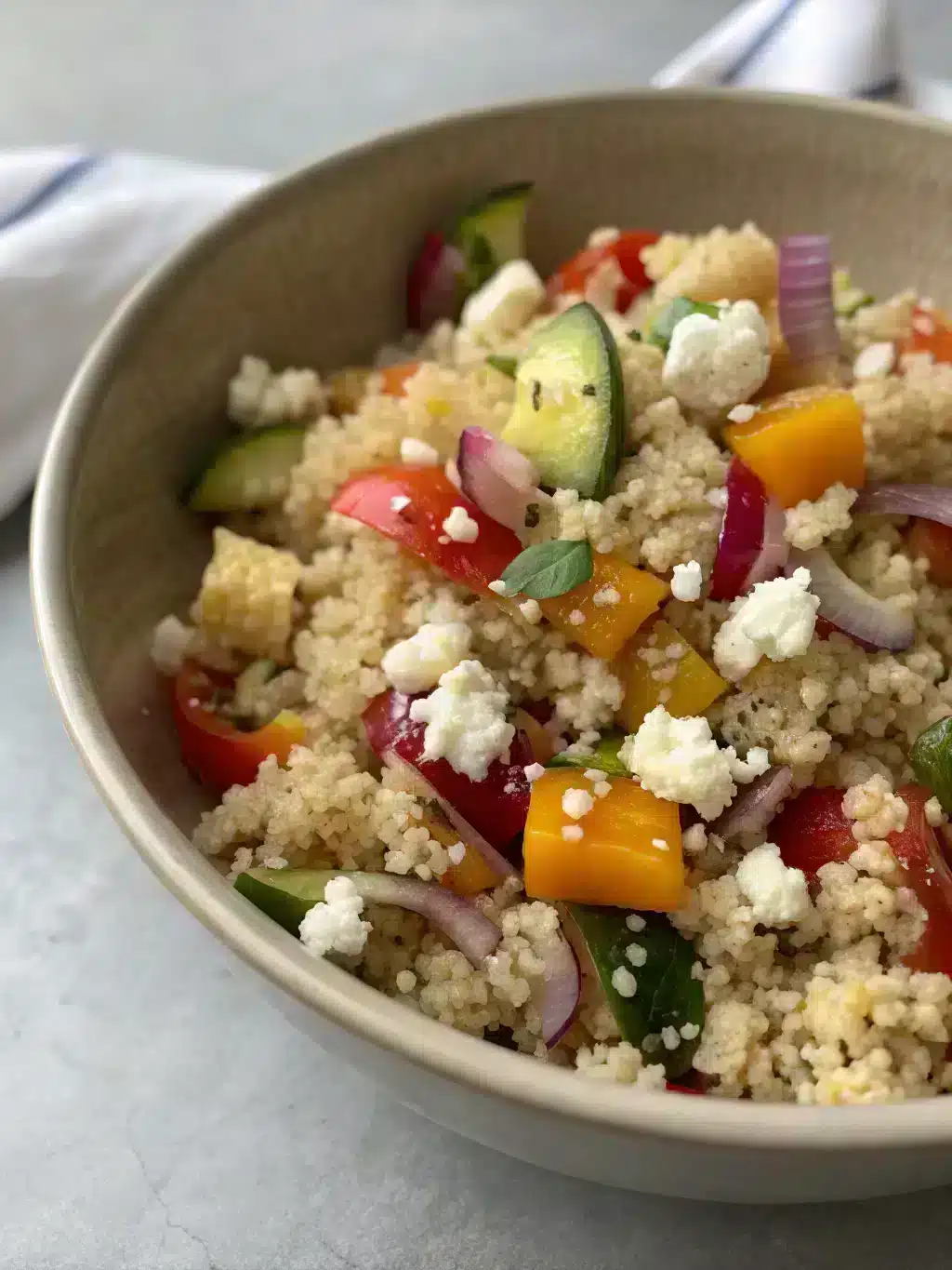 Quinoa salad recipe served in a colorful bowl with fresh herbs and lemon wedges