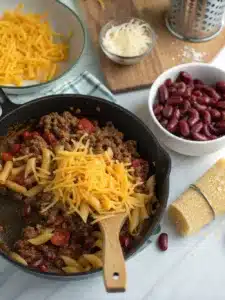 Creamy chili cheese pasta with ground beef and cheddar, topped with sour cream and green onions for a hearty, comforting meal. Ready in 30 minutes!