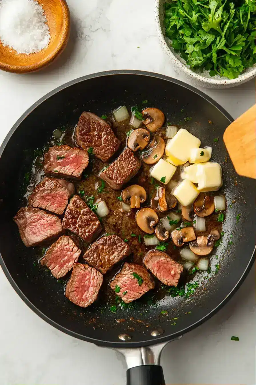 Building the creamy mushroom steak skillet sauce with broth and seasonings