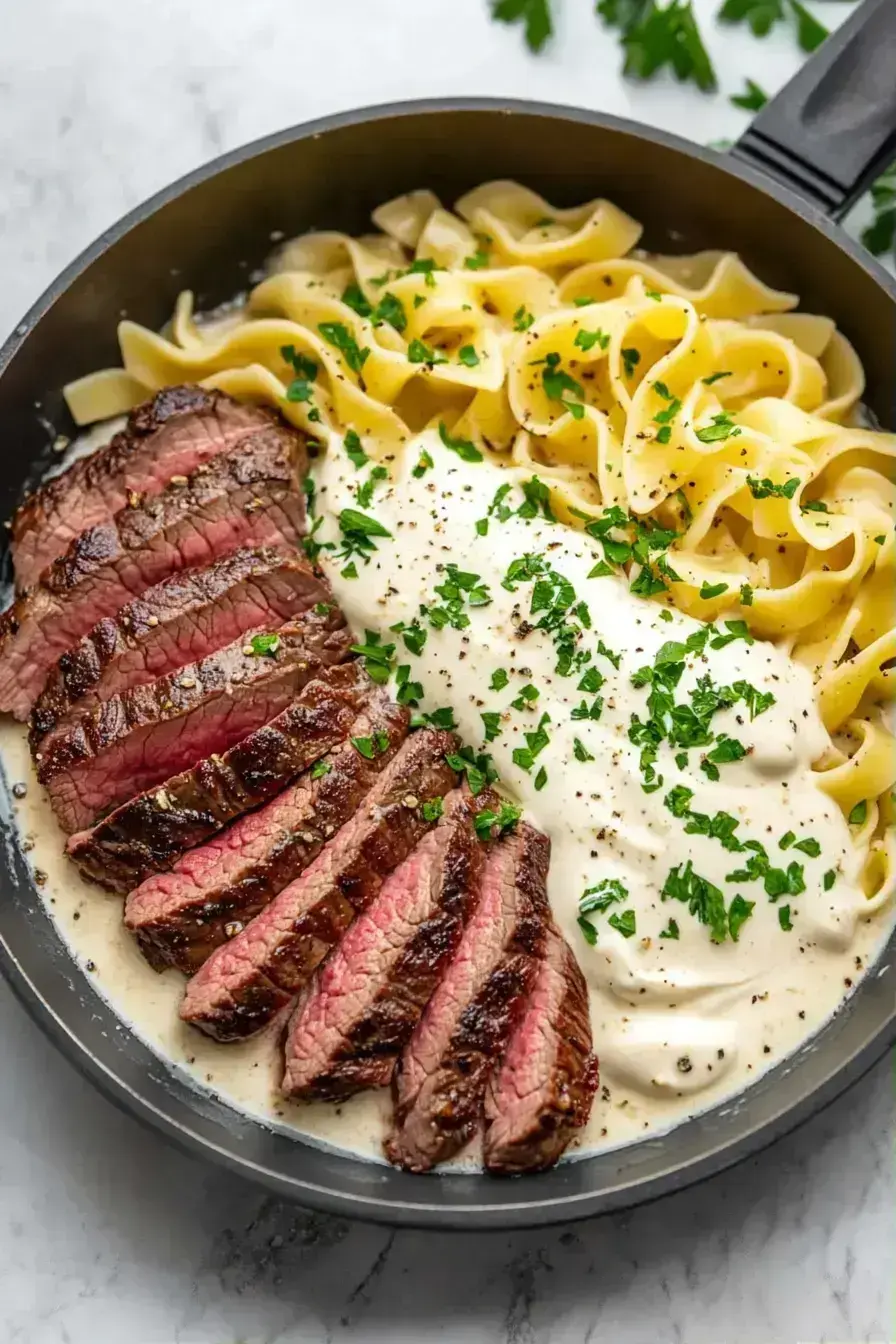 Finished tender stroganoff with egg pasta served in a bowl with fresh parsley