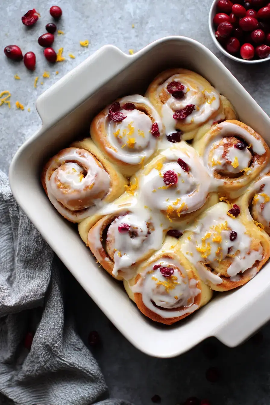 Homemade Cranberry Orange Cinnamon Rolls rising in a baking dish